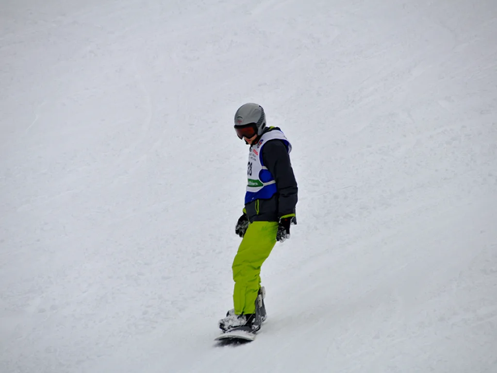 Snowboarder in grüner Hose neben dem Tor.